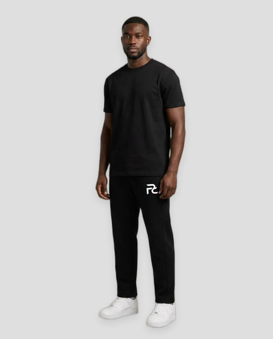 A man modeling a black short-sleeve t-shirt and black sweatpants with a white stylized &
