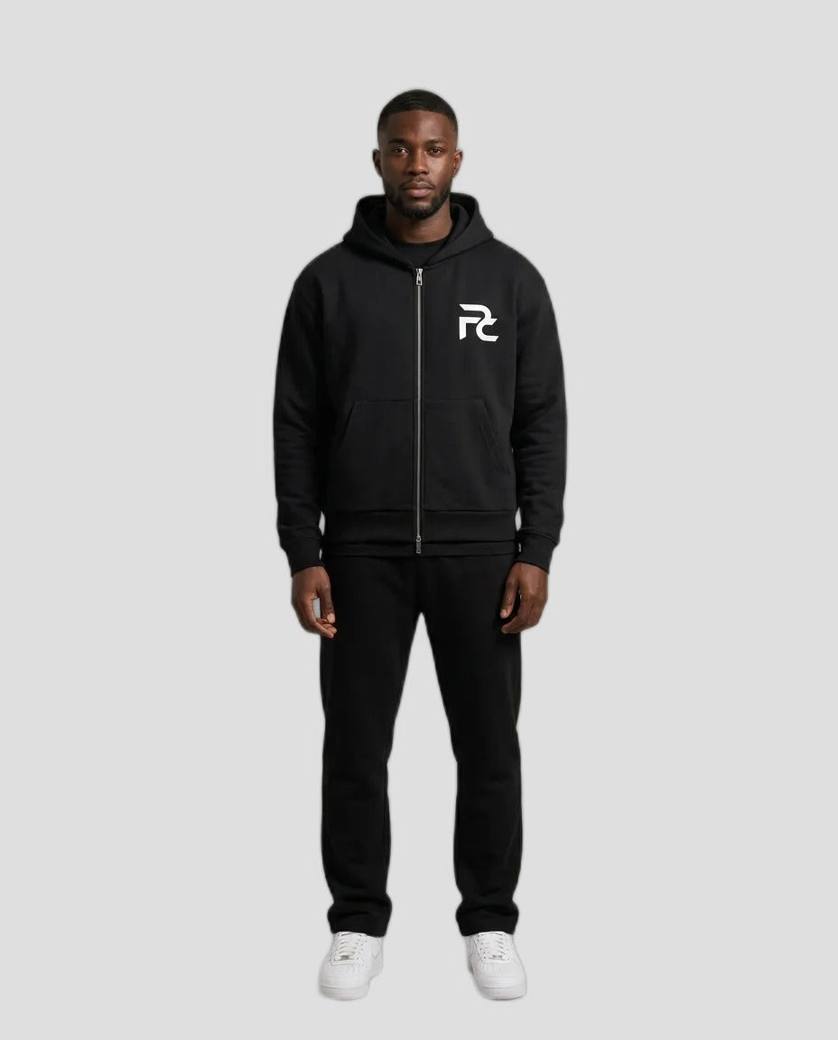 Man wearing the PC Signature Zip Hoodie in black with white PC chest logo, with black pants