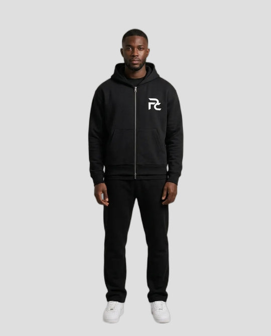 Man wearing the PC Signature Zip Hoodie in black with white PC chest logo, with black pants