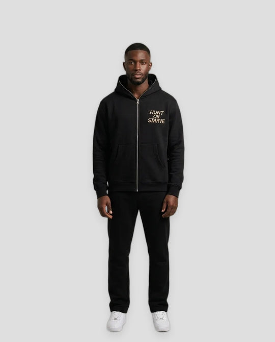 A man modeling a black zip-up hoodie with a gold &