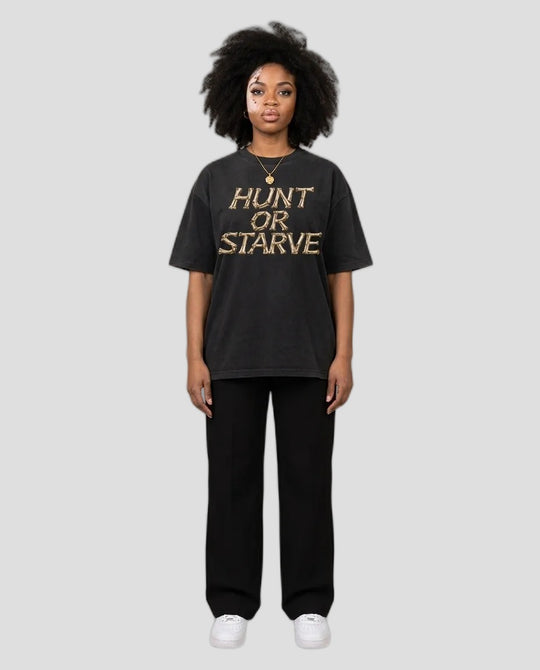 Woman wearing the Washed Hunt or Starve Bone Tee in washed black with tan bone-letter print