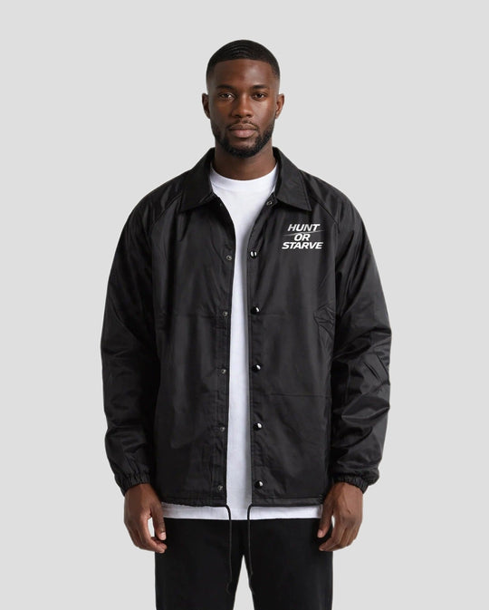 Man wearing the Hunt or Starve Coaches Jacket in black over a white t-shirt, front view