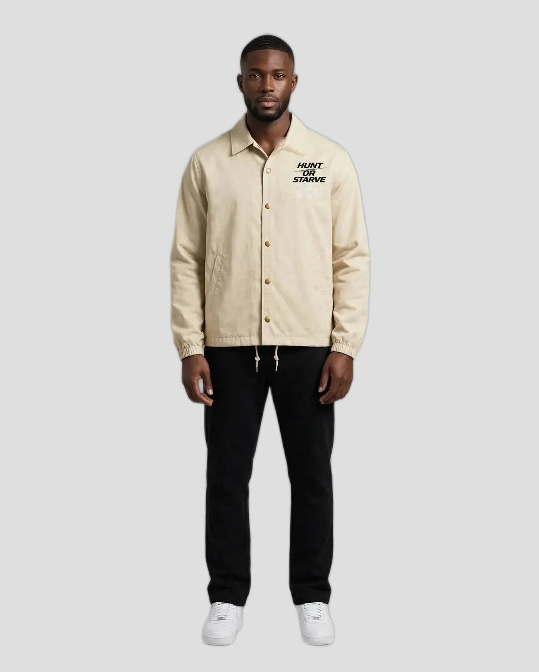 Man wearing the Hunt or Starve Coaches Jacket in beige, front view with small chest logo