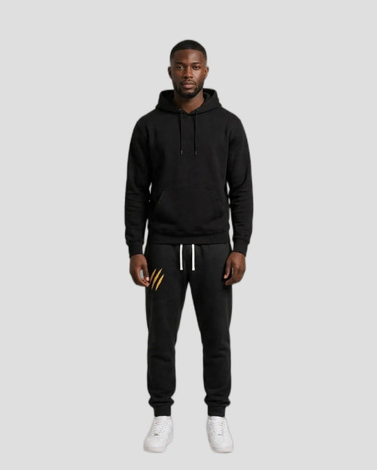 Chris wearing the PRYNCE Claw Marks Sweatpants in black with gold claw marks on the thigh