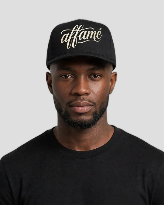 Chris wearing the PRYNCE affamé Black Pro Cap with cream script on a white background
