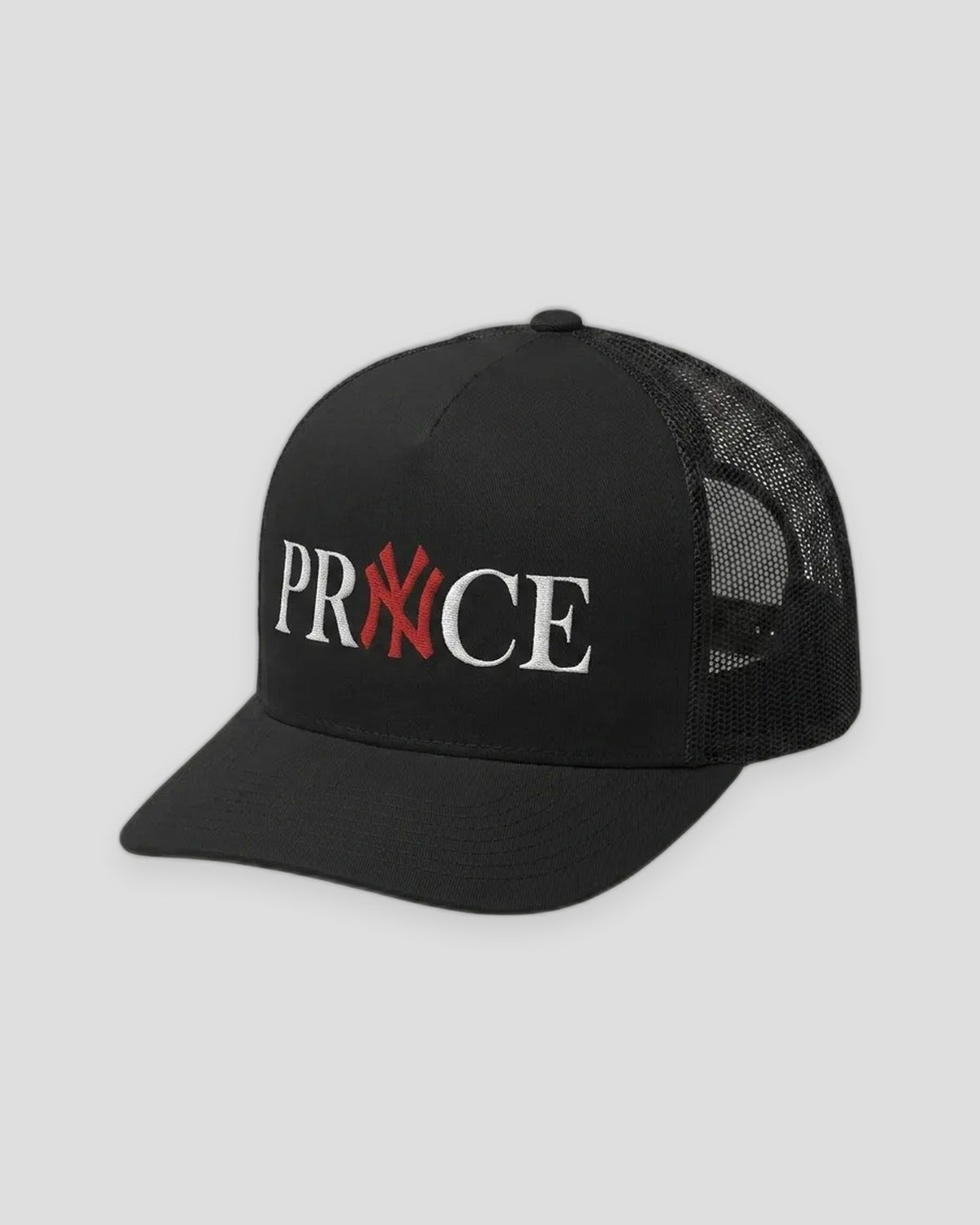 NY PRYNCE Trucker Hat in black, side front view — PRYNCE embroidered in white with a red X, black mesh back