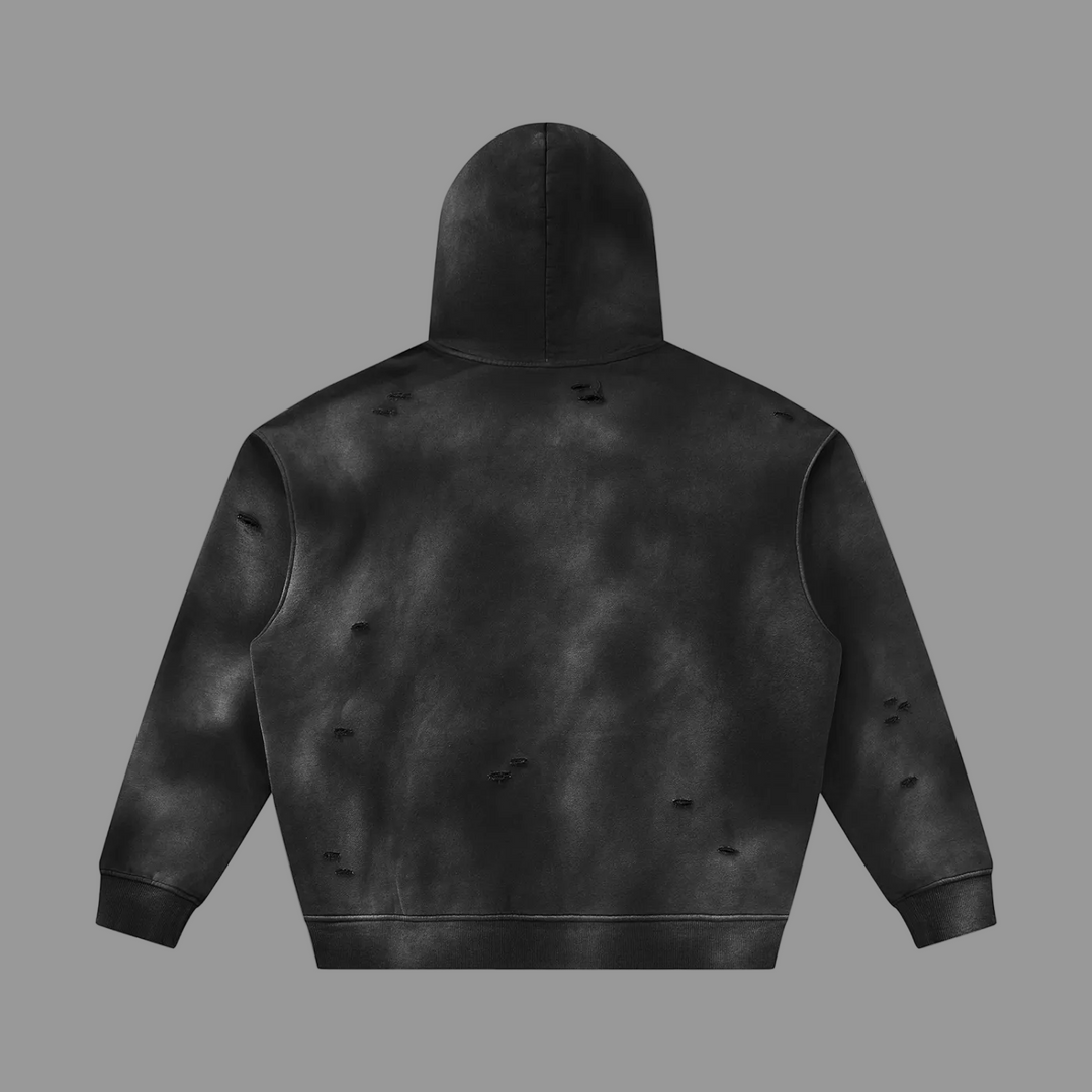 A black distressed hoodie shown from the back, featuring a mottled tie-dye pattern and small rips on the sleeves and back, set against a plain grey background.