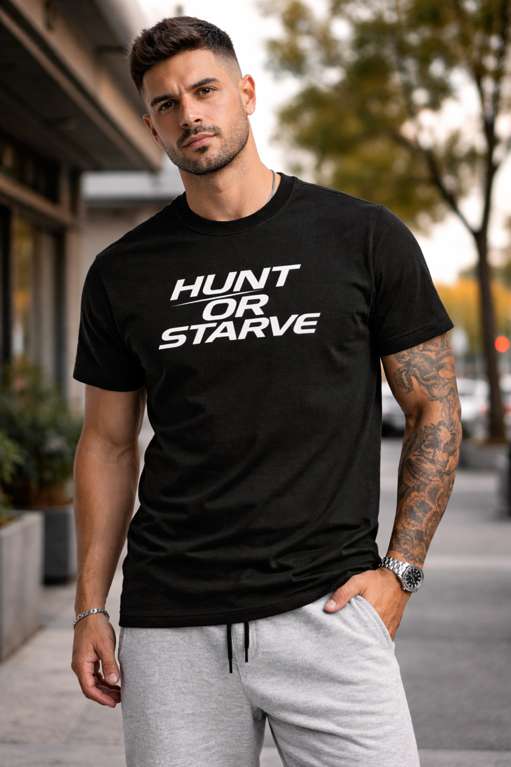 Man wearing a black t-shirt with 'Hunt or Starve' text, standing outdoors.