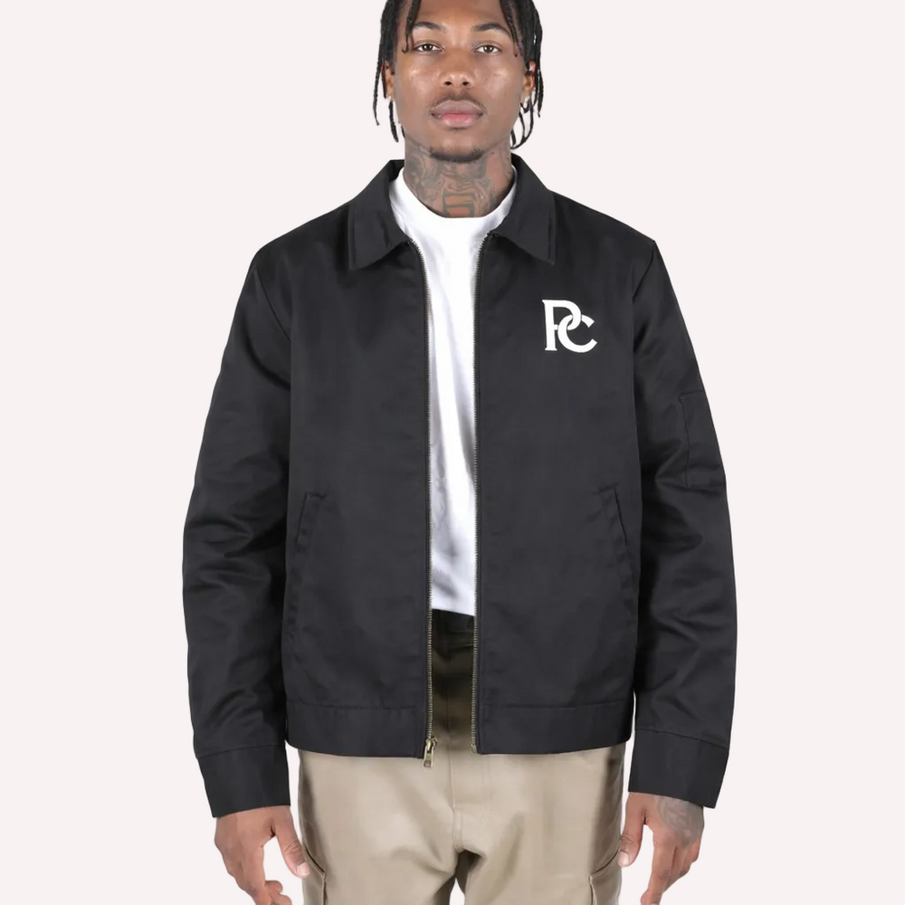 Person wearing a black jacket with a logo on a white background