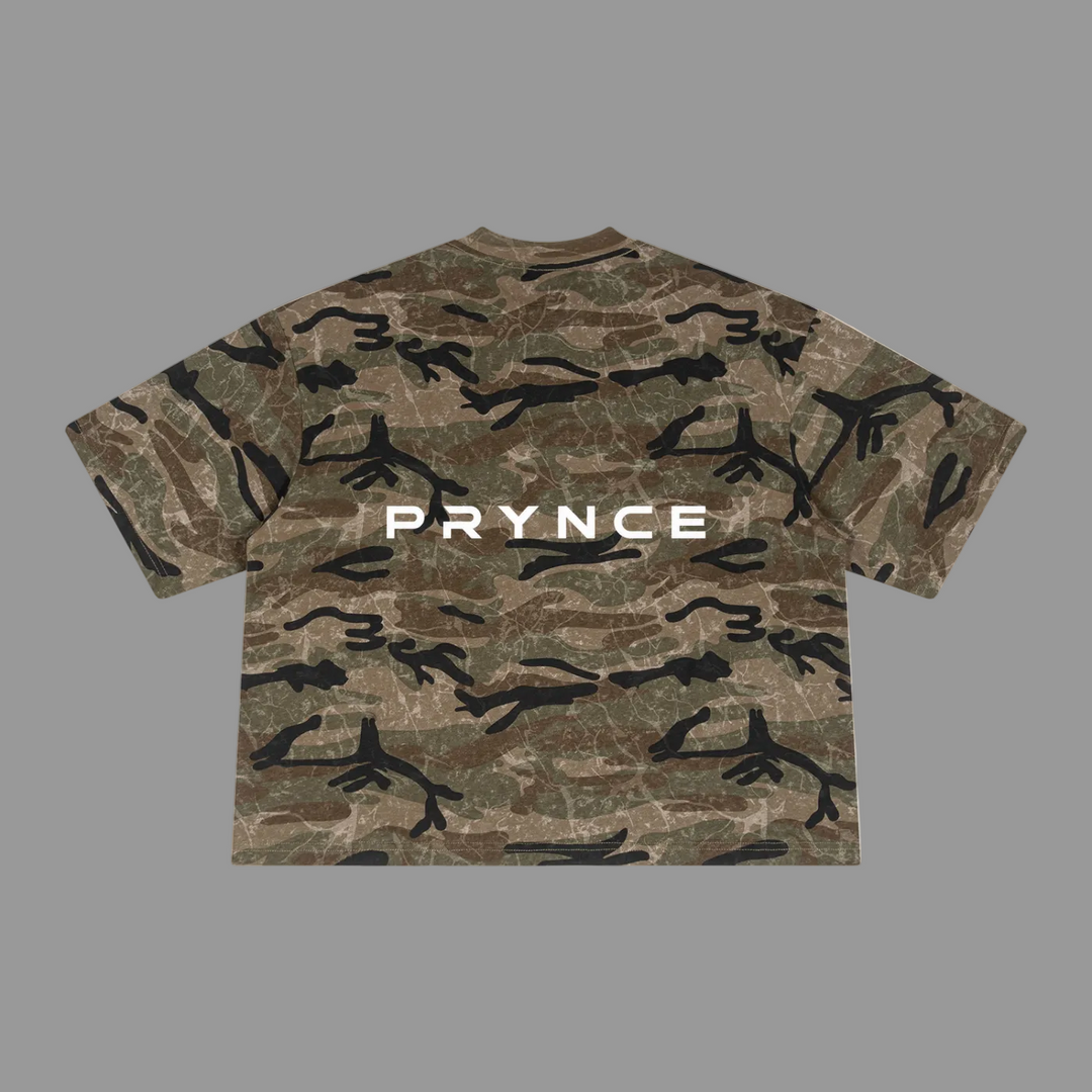 A short-sleeve crewneck t-shirt featuring a brown and green camouflage pattern with black branch-like shapes and the word &