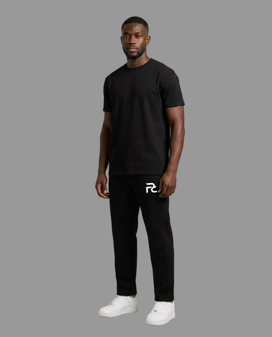 A man modeling a black short-sleeve t-shirt and black sweatpants with a white stylized &