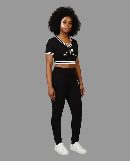 A woman modeling a black short-sleeve crop top with white trim and a white &
