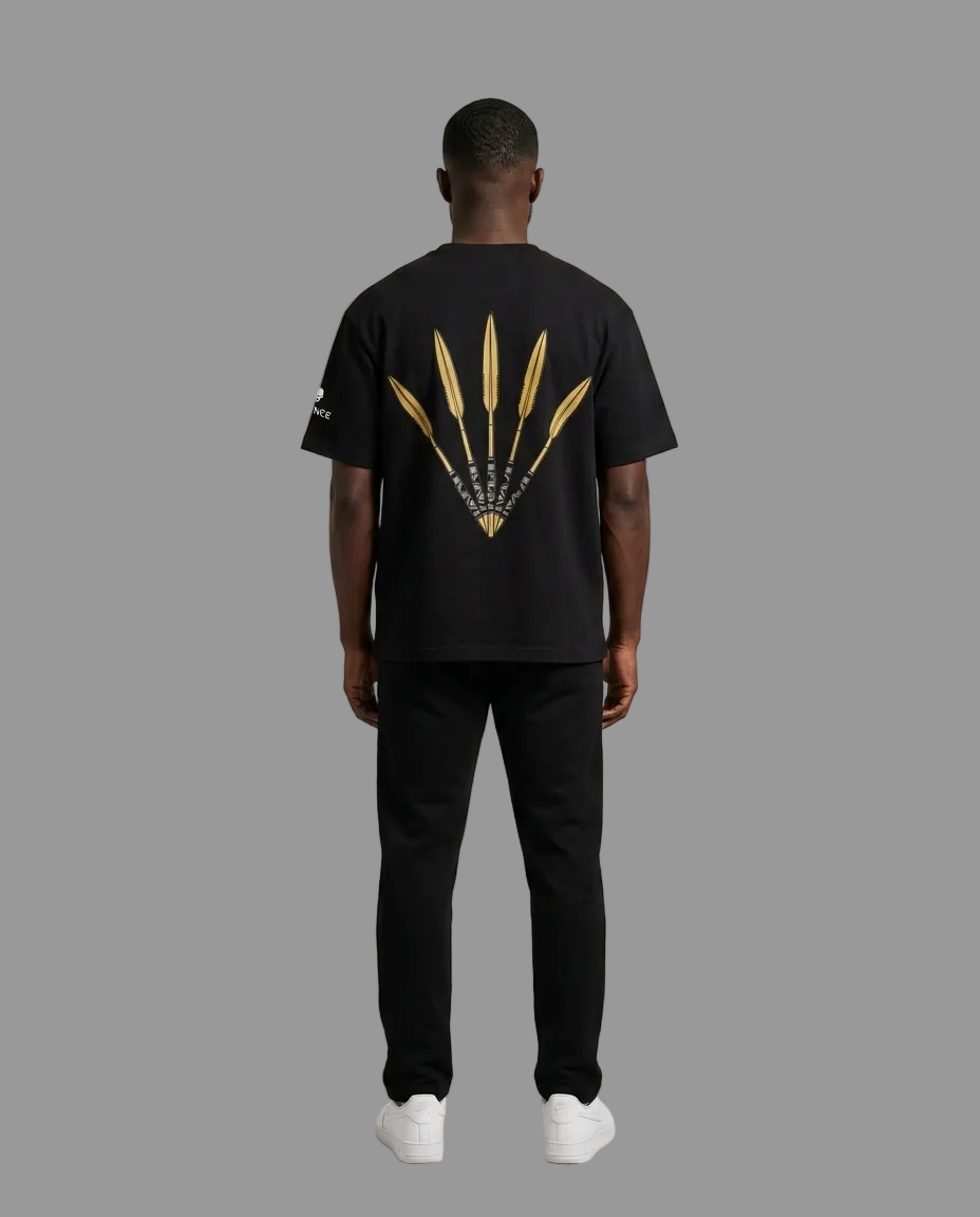 A man viewed from the back wearing a black t-shirt with a large gold graphic of three feathers on the back, paired with black pants and white sneakers, against a neutral beige background.