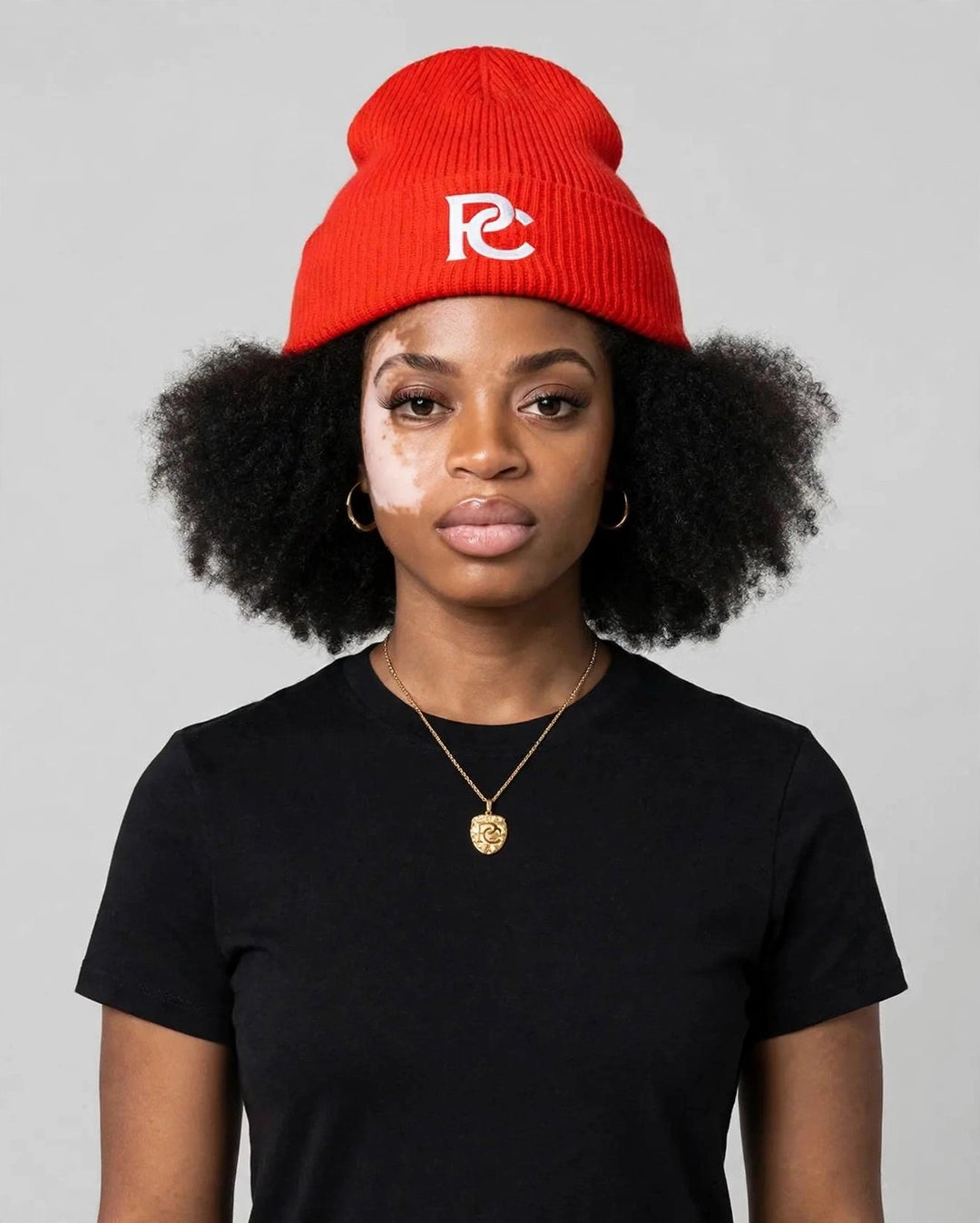 Camila wearing the PC Signature Knit Beanie — red knit beanie with white interlocked PC monogram