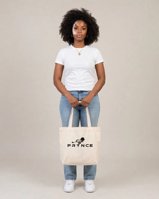 Camila holding the PRYNCE Lion Lockup Tote Bag in Cream with the black running lion logo, full body studio shot