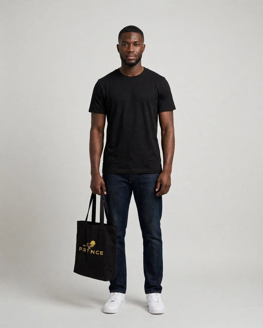 Chris holding the PRYNCE Lion Lockup Tote Bag in Black with the gold running lion logo, full body studio shot
