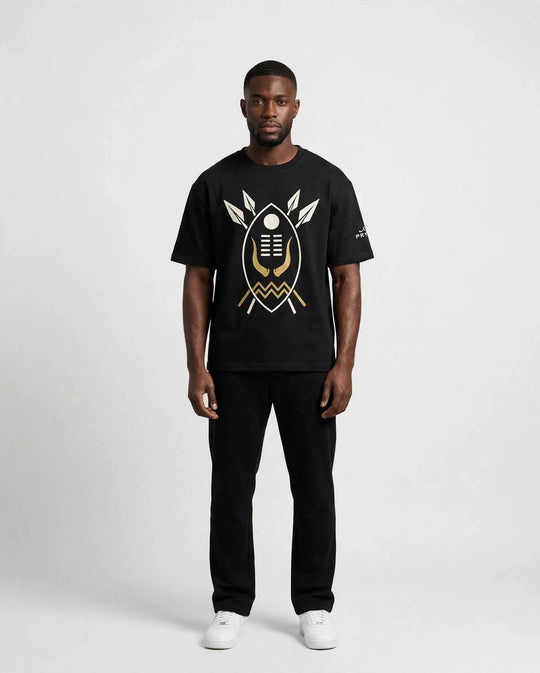 Chris wearing the PRYNCE AFRICA Warrior Shield Tee in black with cream and gold shield print, full body